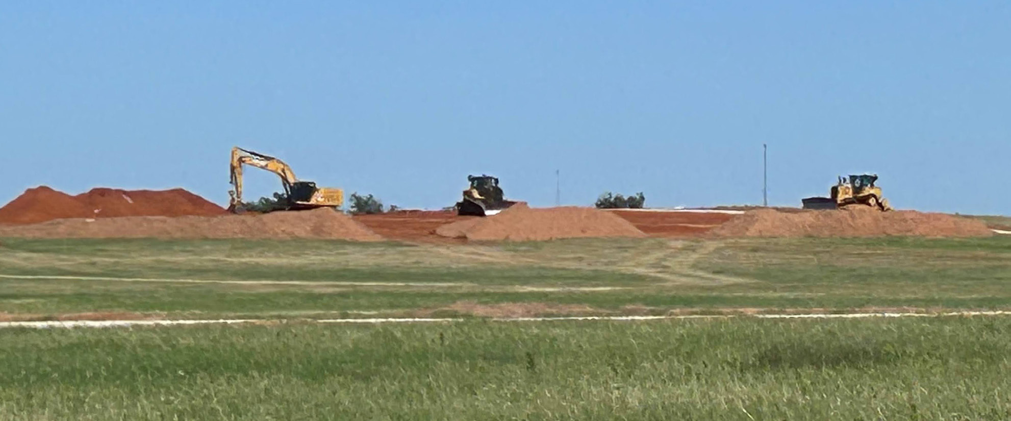 PLAYING IN THE DIRT In this long-distance view, bulldozers and excavator resemble Tonka trucks sitting in a pile of dirt just waiting for a kid to come and move some dirt. The real-life machines are part of the construction equipment on the ZSS solar project.