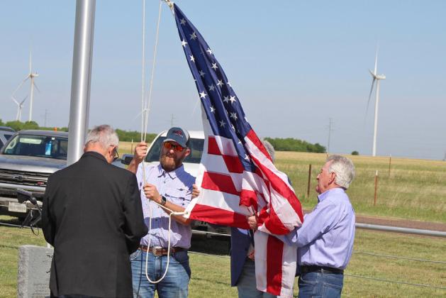 WINDY DAY BESIDE THE WIND FARM At a ceremony to raise the U.S. flag on the newly dedicated flagpole at the Gilliland Cemetery April 25, four veterans (from left) Bill Baty of Horseshoe Bay,Texas; Steve King of Haskell,Texas; Gary Baty of Horseshoe Bay and Frank Sanders of Horseshoe Bay, high winds lofted the colors skyward. A scheduled honor guard was canceled. | CHANCE BATY