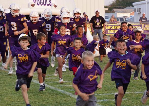MES FLAG FOOTBALL TEAMS BRING ON THE MOGULS Munday Elementary students on the Munday Flag football teams help the Moguls take the field on Friday. | LACI BOWMAN