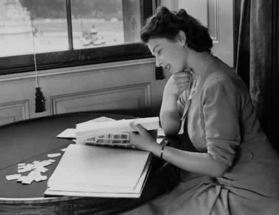 Queen Elizabeth II enjoying her stamp collection Courtesy Photo