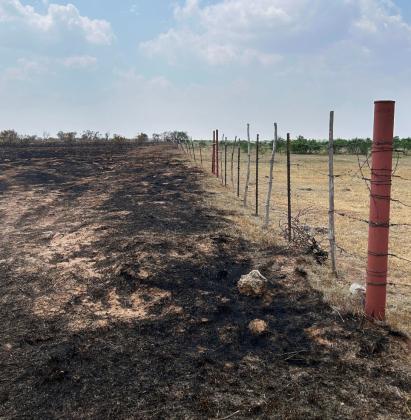 FENCED IN In Knox County this week, a barbed wire fence seems to have kept a fire from crossing a road. Firefighters often travel along the fences soakingdownthevegetation— also known as fuel—to keep fires from spreading onto other properties. Ideally, a fence row is open enough for a fire truck to drive along it.