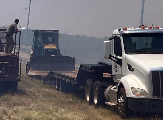 COUNTY EQUIPMENT UNLOADED The county bulldozer being unloaded while chief deputy Ryan Thrash looks on. In rural areas firefighters rely on cooperation from everyone in order to perform their duties. This fire east of Munday had 2 volunteer fire departments, a state trooper, sheriff’s office, and county employees all as part of the effort to get the fire out |TROY PARTON
