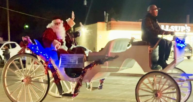 SANTA CLAUS IS COMING TO TOWN Santa arrives being carried by Marc Flores of Poppies Pony Parties.