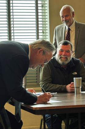 BOND OF OFFICE Don Thompson of Munday (left) signed the surety bond required to serve the unexpired term of county judge on Dec. 6, as Judge Stan Wojcik and commissioners look on. | NEWS-COURIER