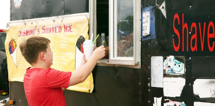 AT KNOX CITY'S THIRD OF JULY CELEBRATION rain didn't dampen enthusiasm for refreshments—Seth Hodges is taking care of business at the snow cone stand. MORE PHOTOS. PAGE 6 | SHER BATI PHOTOS