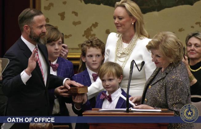 ELECTED TX SPEAKER State Rep. Dustin Burrows was administered the oath of office as Speaker of the Texas House by Secretary of State Jane Nelson (right) during opening day ceremonies on the House floor on Tuesday, Jan. 14, 2025, as Burrows’wife, Elisabeth (in white dress), and children look on. | BOB DAEMMRICH FOR THE TEXAS TRIBUNE