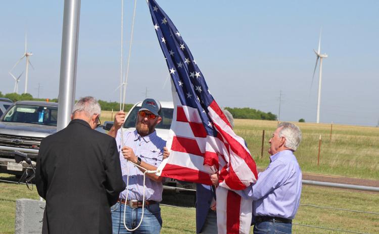 WINDY DAY BESIDE THE WIND FARM At a ceremony to raise the U.S. flag on the newly dedicated flagpole at the Gilliland Cemetery April 25, four veterans (from left) Bill Baty of Horseshoe Bay,Texas; Steve King of Haskell,Texas; Gary Baty of Horseshoe Bay and Frank Sanders of Horseshoe Bay, high winds lofted the colors skyward. A scheduled honor guard was canceled. | CHANCE BATY